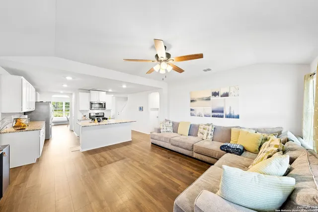 a living room with furniture kitchen view and a wooden floor