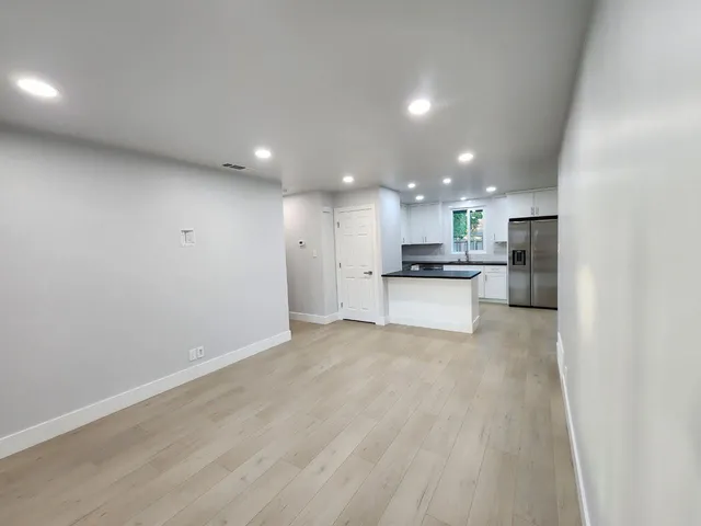a view of kitchen with kitchen island a sink wooden floor and stainless steel appliances