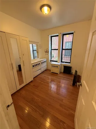 a view of an empty room with a window and wooden floor