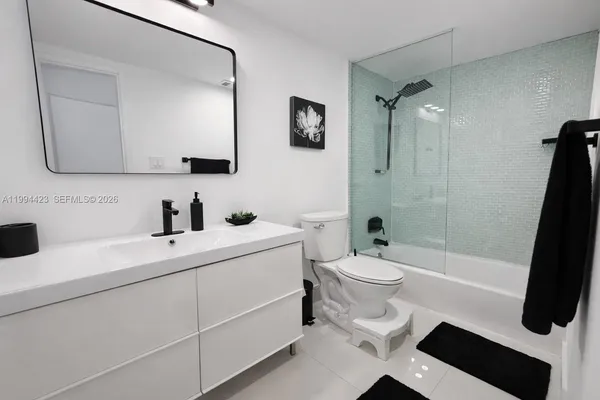 a bathroom with a sink a toilet a mirror a vanity and shower