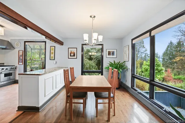 a dining room with wooden floor a chandelier a wooden table and chairs