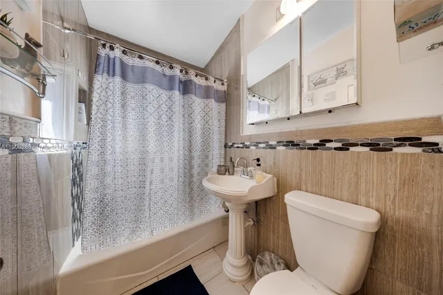 a bathroom with a sink a toilet a mirror and shower curtain