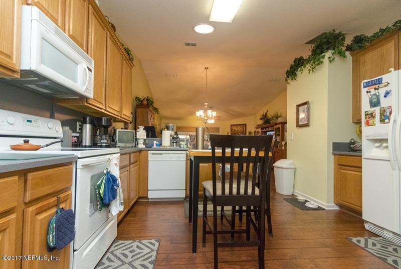 3120 Ravines Road Middleburg, FL 32068 - Photo 14 of 37 a kitchen with stainless steel appliances granite countertop a refrigerator a stove and white cabinets with wooden floor