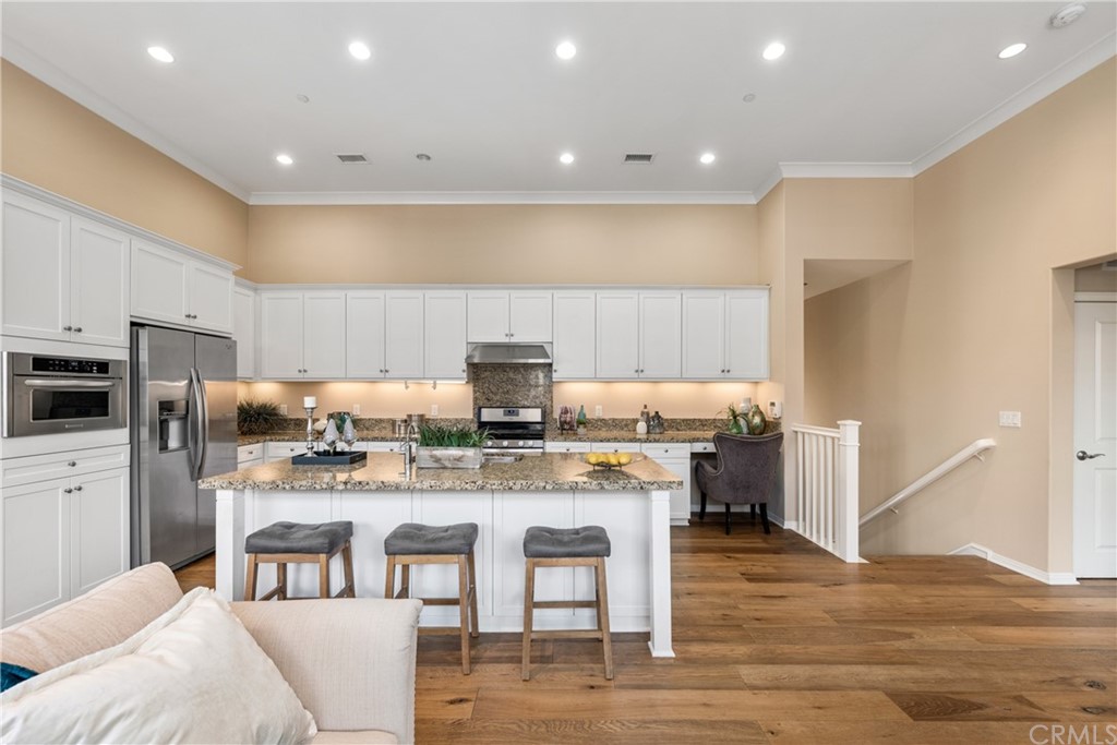 97 Mayfair Irvine, CA 92620 - Photo 10 of 42 a large kitchen with kitchen island granite countertop a stove a sink a refrigerator and white cabinets with wooden floor
