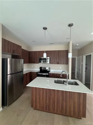 a kitchen with kitchen island a counter top a sink and refrigerator