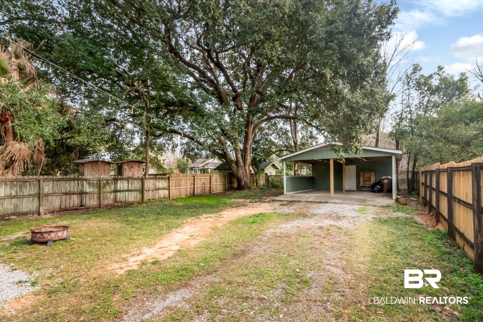 2157 Homewood Street Mobile, AL 36606 - Photo 31 of 36 View of yard with a patio, dirt driveway, an outdoor fire pit, an attached carport, and a fenced backyard