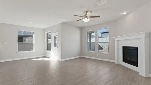 a view of an empty room with wooden floor and a fireplace