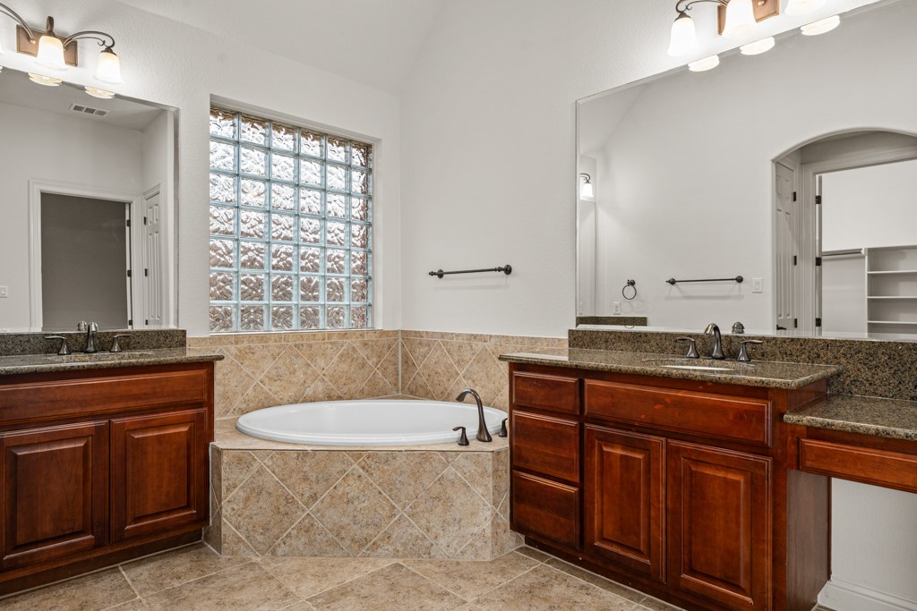651 Shelf Rock Road Driftwood, TX 78619 - Photo 23 of 38 a spacious bathroom with a granite countertop double vanity sink a mirror and a bathtub
