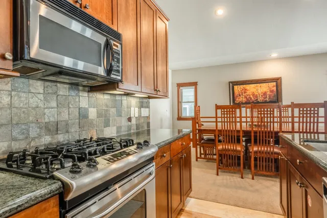 a kitchen with stainless steel appliances a stove a sink a dining table and chairs