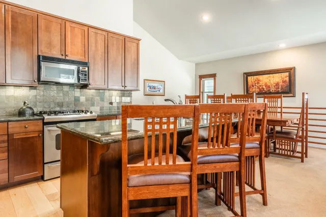 a kitchen with stainless steel appliances granite countertop a table and chairs