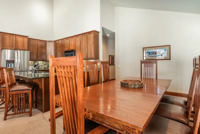 a kitchen with stainless steel appliances granite countertop a refrigerator a stove a sink a dining table and chairs with wooden floor