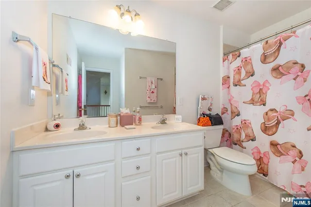 a bathroom with a double vanity sink mirror and toilet