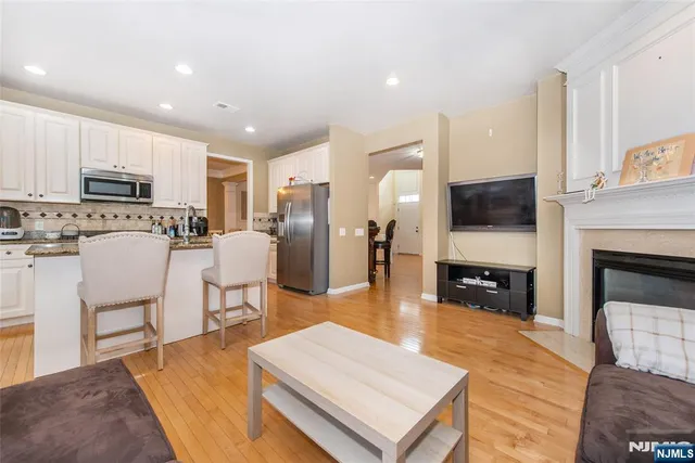 a living room with stainless steel appliances furniture a fireplace a flat screen tv and view kitchen