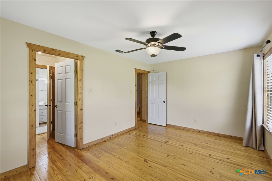 903 Summit Street Round Rock, TX 78664 - Photo 12 of 38 Primary Bedroom with wood floors and trim, high ceilings, lots of natural light, with a walk in closet that leads into the downstairs full bath. Neultral pallet and lots of natural lighting with a ceiling fan.