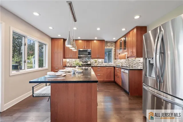 a kitchen with stainless steel appliances granite countertop a refrigerator a sink a stove a microwave and wooden cabinets