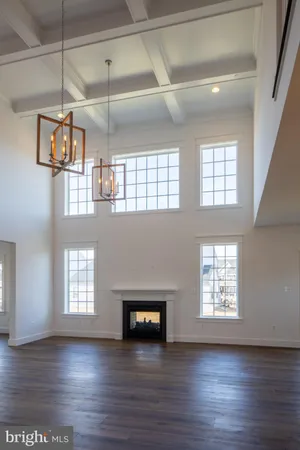 a view of a livingroom with wooden floor a ceiling fan and windows