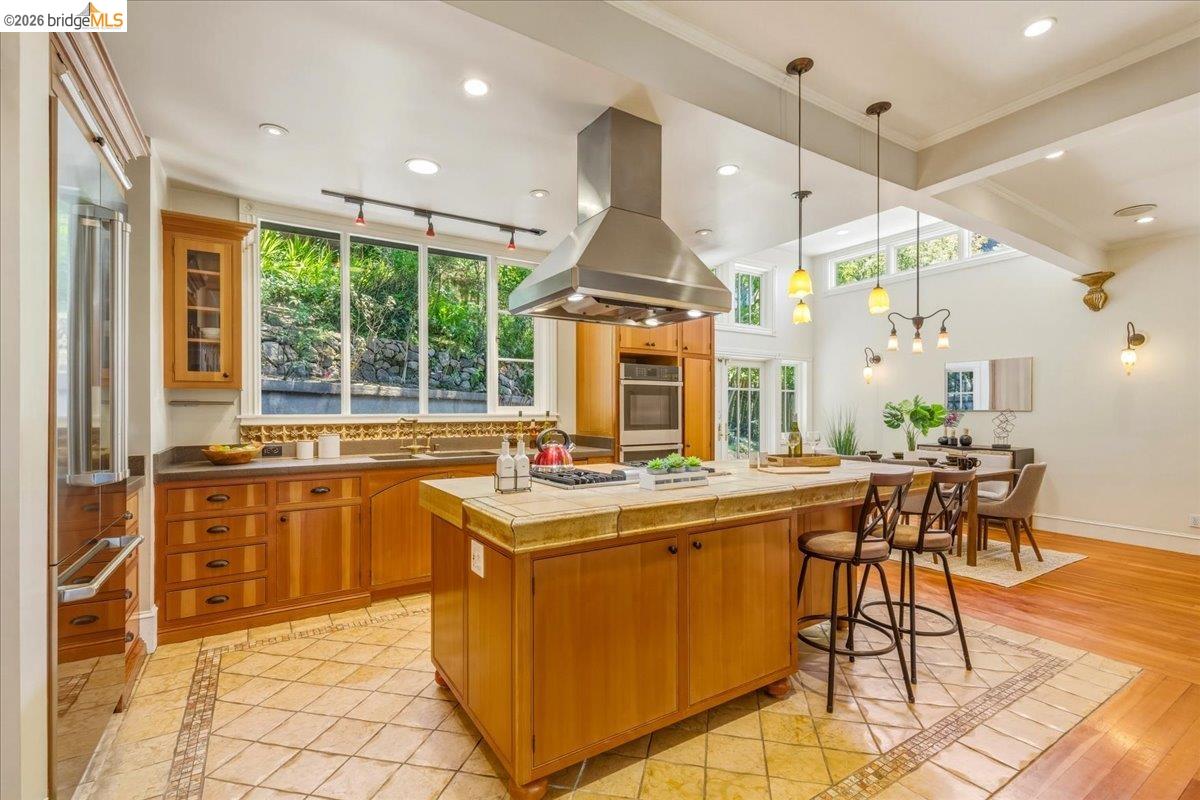 1631 La Vereda Road Berkeley, CA 94709 - Photo 7 of 42 Kitchen featuring wood cabinetry, stainless steel appliances, and a central island with a tiled countertop