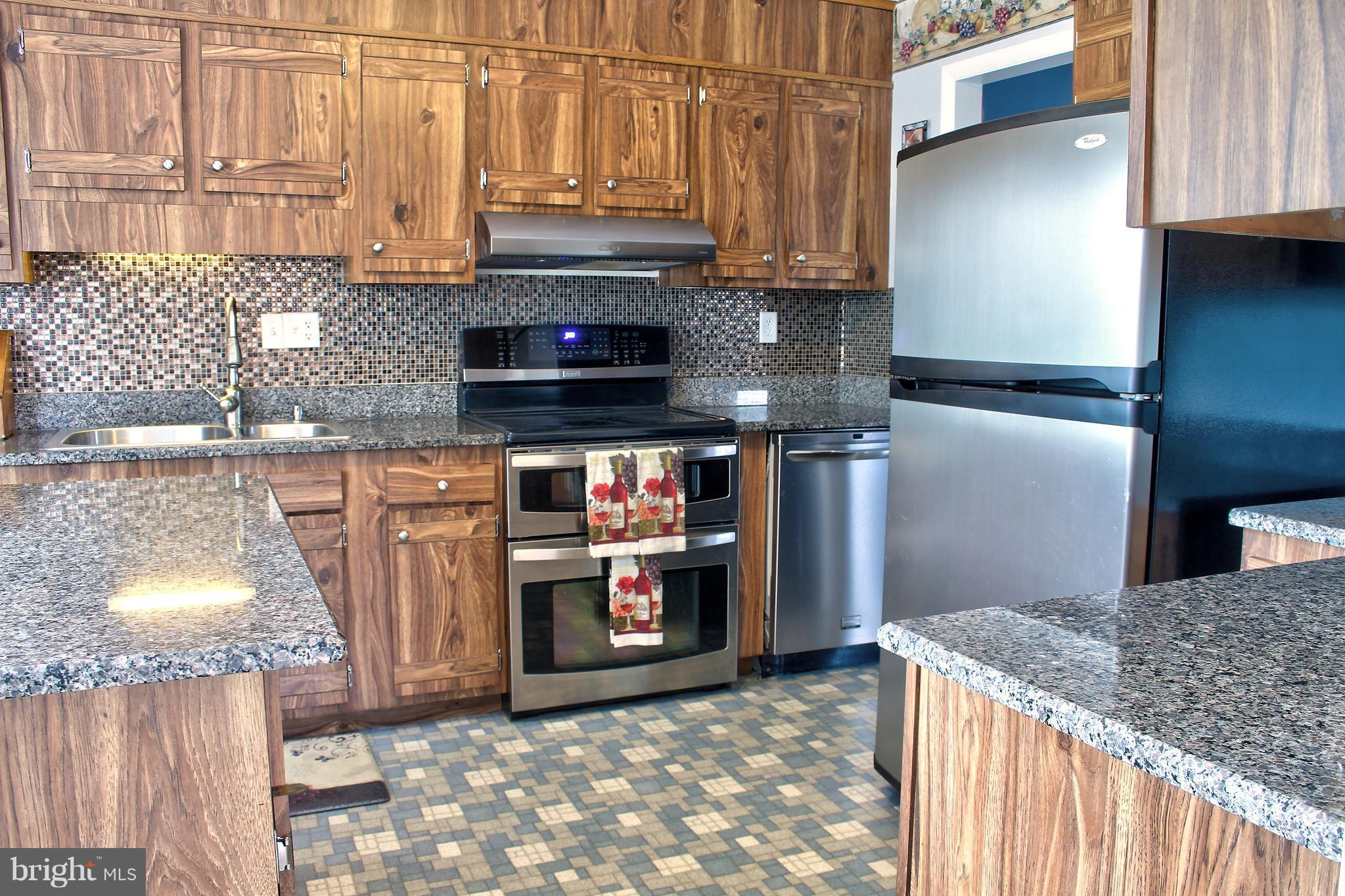 2409 Gillis Road Mount Airy, MD 21771 - Photo 7 of 27 a kitchen with stainless steel appliances granite countertop a refrigerator a stove and a sink with wooden cabinets