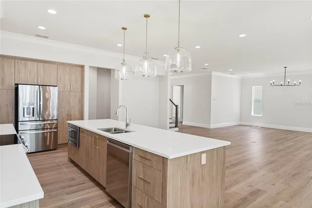 a kitchen with stainless steel appliances granite countertop a sink a refrigerator and a stove top oven with wooden floor