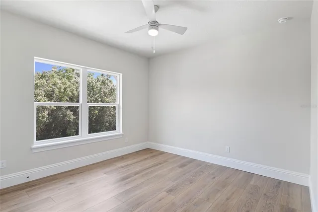 a view of empty room with wooden floor and fan