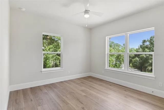 an empty room with wooden floor and windows