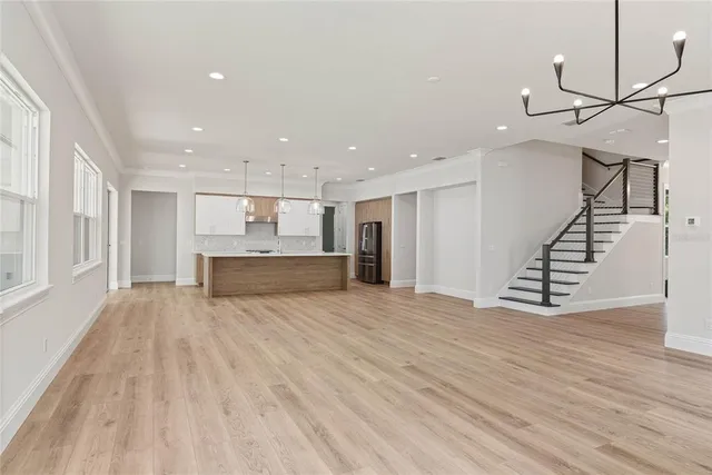 a view of an empty room with wooden floor and stairs
