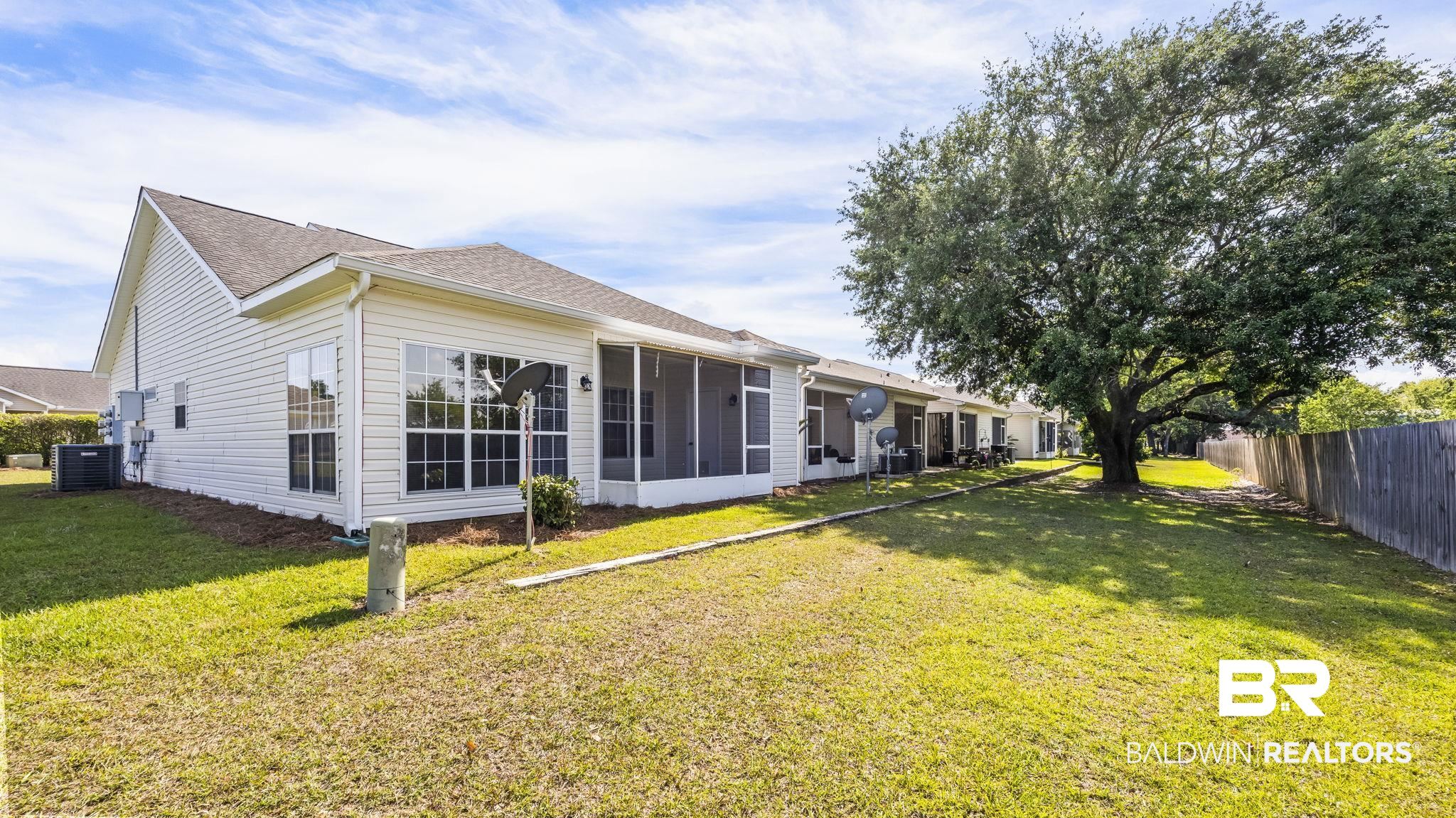 2651 South Juniper Street, Unit 705 Foley, AL 36535 - Photo 25 of 37 Expansive green space featuring a mature shade tree and a wooden privacy fence