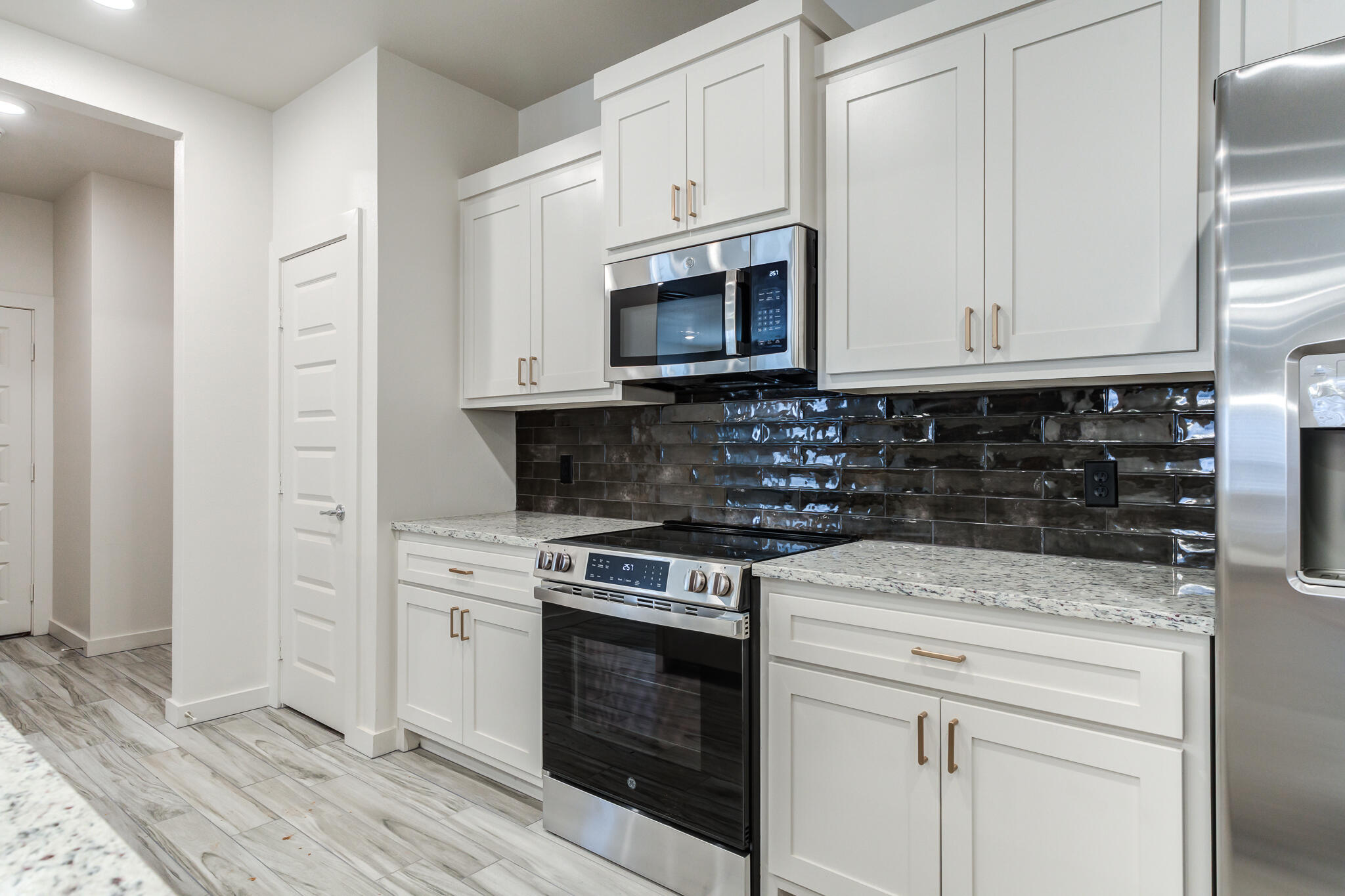 7046 41st Street Lubbock, TX 79407 - Photo 11 of 28 a kitchen with stainless steel appliances granite countertop a stove a microwave and a white cabinets
