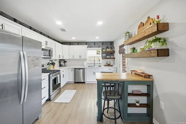 a kitchen with kitchen island a counter top space a sink stainless steel appliances and cabinets