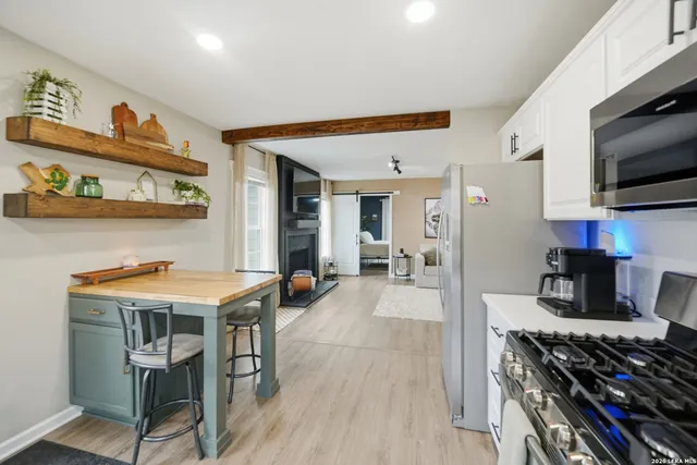 a kitchen with stainless steel appliances a stove a table and chairs in it