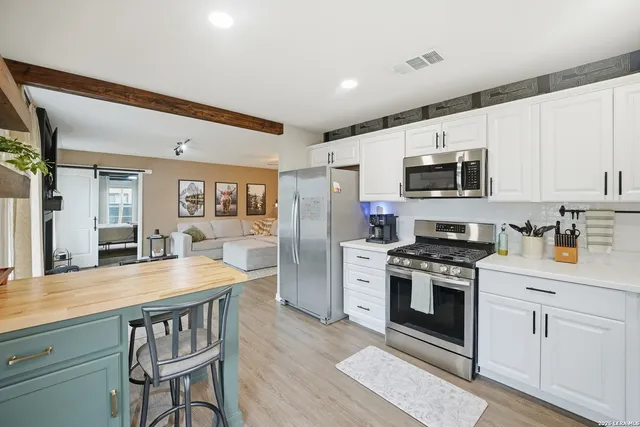 a kitchen with granite countertop a stove top oven a sink dishwasher a dining table and chairs with wooden floor