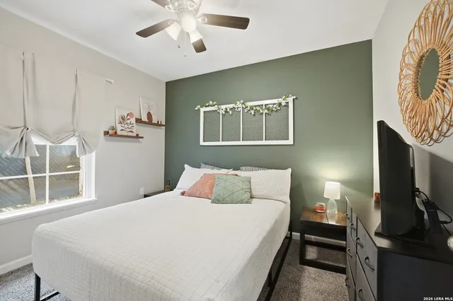 a bedroom with a bed and a flat tv screen on the dresser