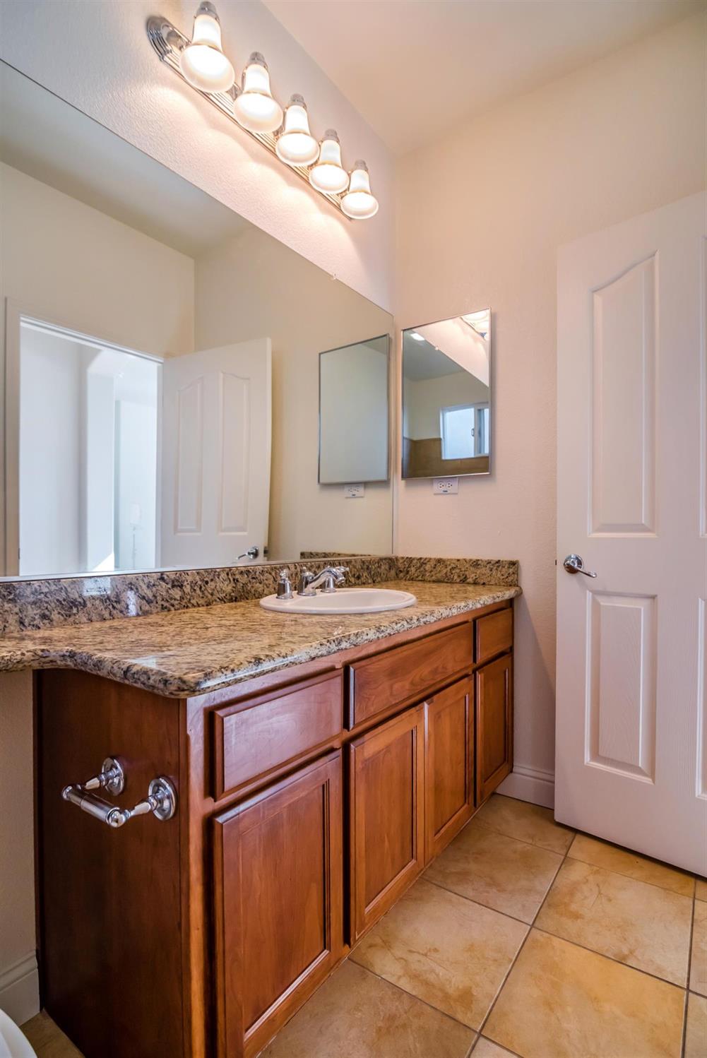 11737 Brook Valley Way Rancho Cordova, CA 95742 - Photo 21 of 25 a bathroom with a granite countertop sink a mirror and a vanity