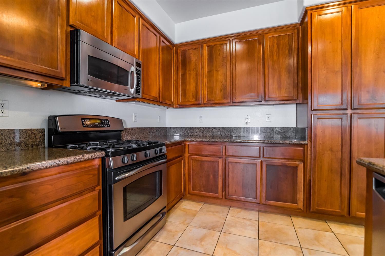 11737 Brook Valley Way Rancho Cordova, CA 95742 - Photo 22 of 25 a kitchen with granite countertop a stove top oven microwave and cabinets