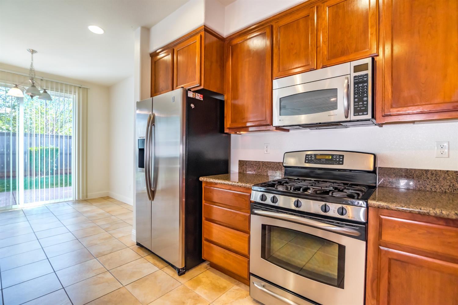 11737 Brook Valley Way Rancho Cordova, CA 95742 - Photo 10 of 25 a kitchen with granite countertop a stove microwave and refrigerator