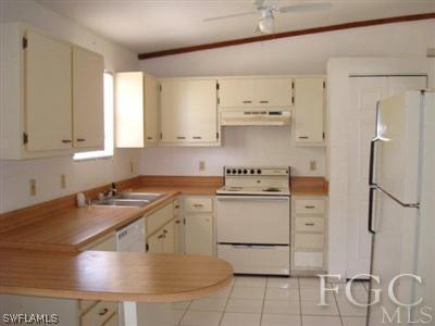 4204 9th Street Southwest Lehigh Acres, FL 33976 - Photo 4 of 10 a room with a stove a sink and a refrigerator