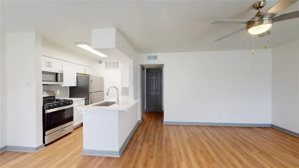 a kitchen with stainless steel appliances a stove top oven a refrigerator a sink and dishwasher with wooden floor