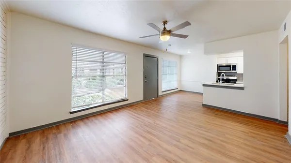 a view of an empty room with wooden floor and a window