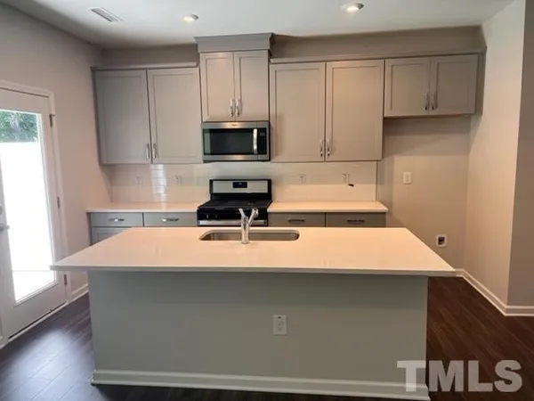 a room with kitchen island sink and cabinets