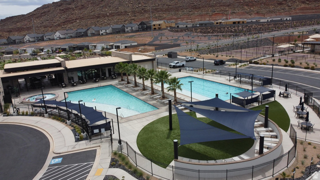 1693 Devils Gdn Lane Washington, UT 84780 - Photo 46 of 64 Community pool and spa area featuring a modern recreational building, multiple shaded seating areas, and surrounding hardscape