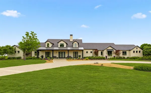 a view of a big house with a big yard and large trees