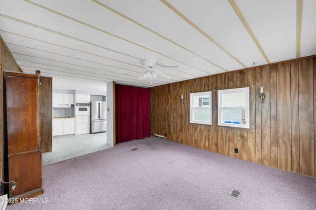 a view of hallway with an empty room and wooden floor