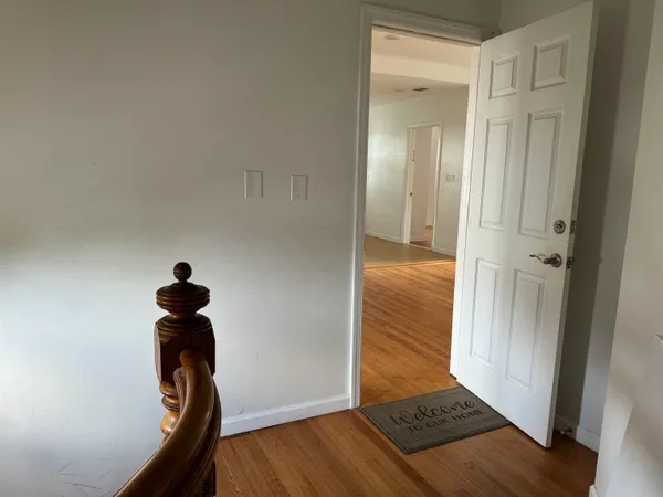 a view of a hallway to a room with wooden floor and staircase