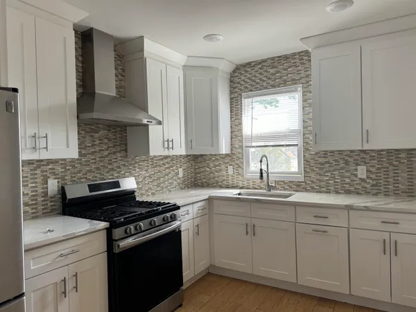 a kitchen with white cabinets appliances a sink and a window