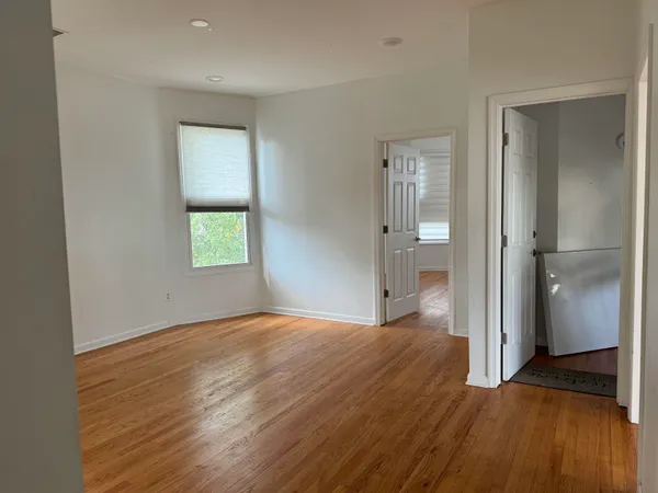 a view of empty room with wooden floor and a window