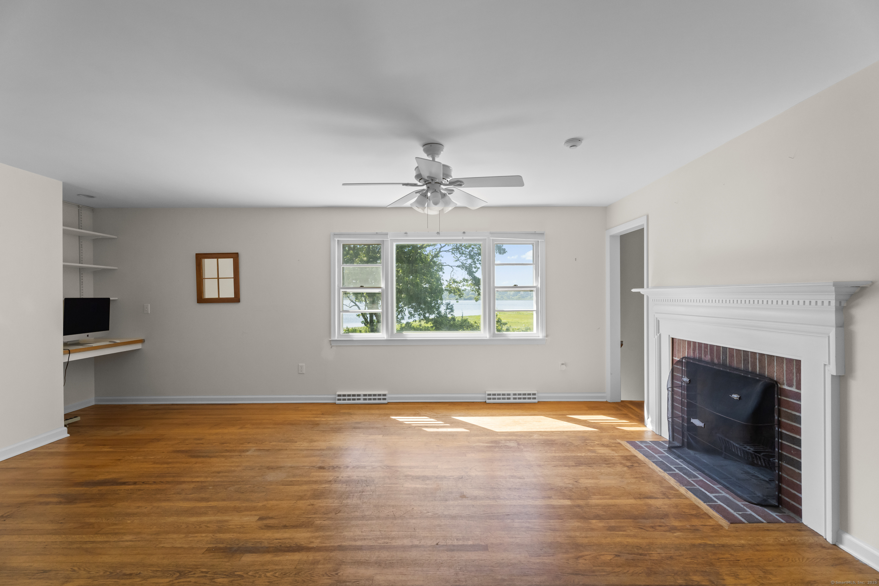 301 Osbrook Point Stonington, CT 06379 - Photo 14 of 39 an empty room with wooden floor fireplace and windows