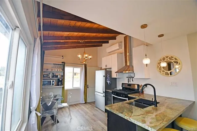 a kitchen with stainless steel appliances granite countertop a stove a sink dishwasher and a dining table with wooden floor