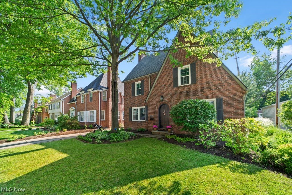English style home with a front yard, brick siding, and a chimney