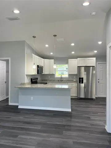 a view of kitchen with stainless steel appliances granite countertop refrigerator and stove top oven