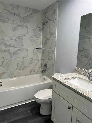 a bathroom with a granite countertop toilet a sink and bathtub